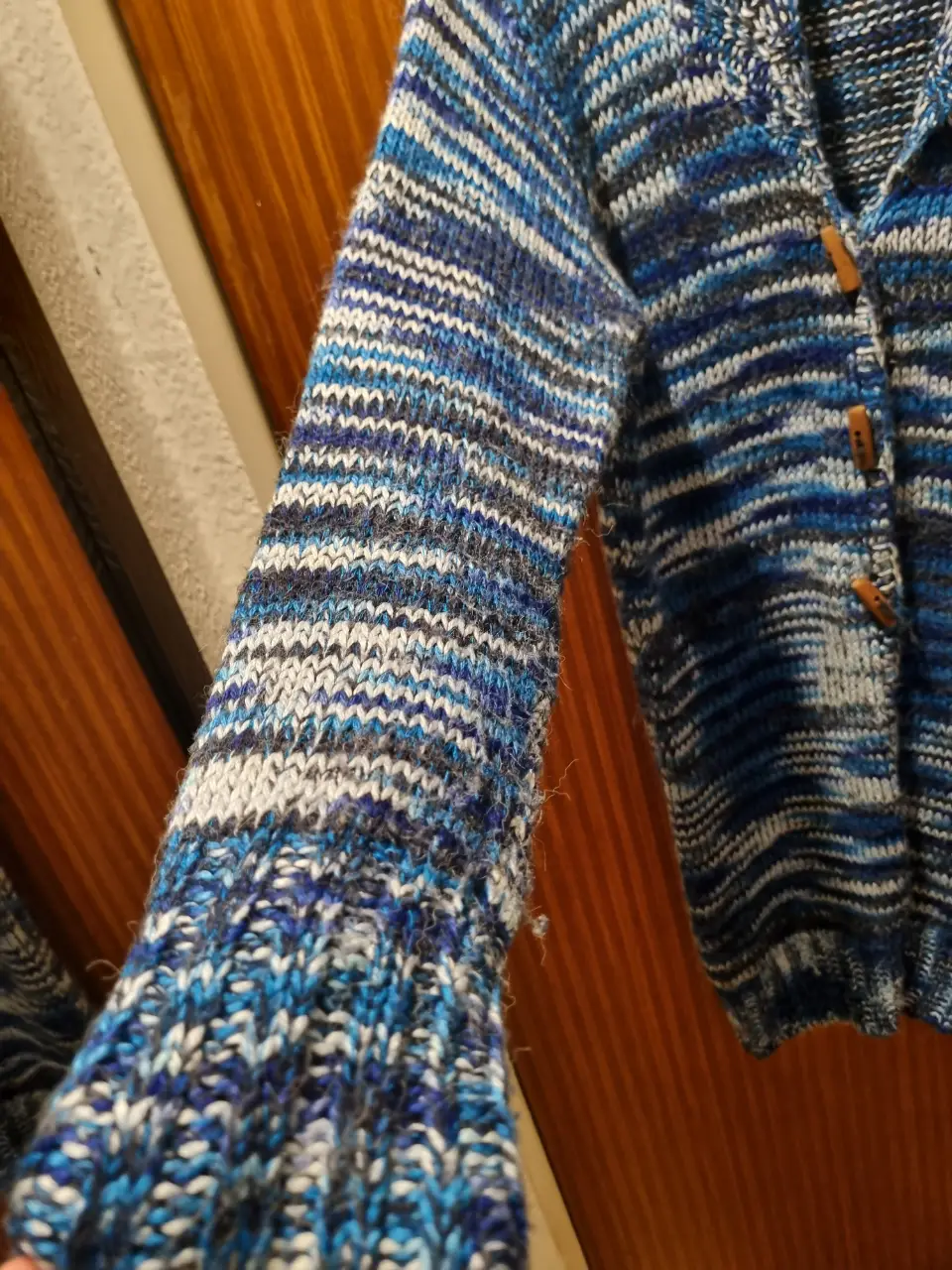 Cardigan de lana tejido a rayas en tonos azules y blancos, con botones de madera y cuello amplio. Ideal para un look casual y abrigado.