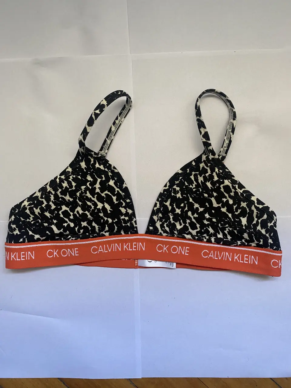Corpiño Calvin Klein CK One con estampado animal print. Banda inferior naranja con logo de la marca. Talle M.