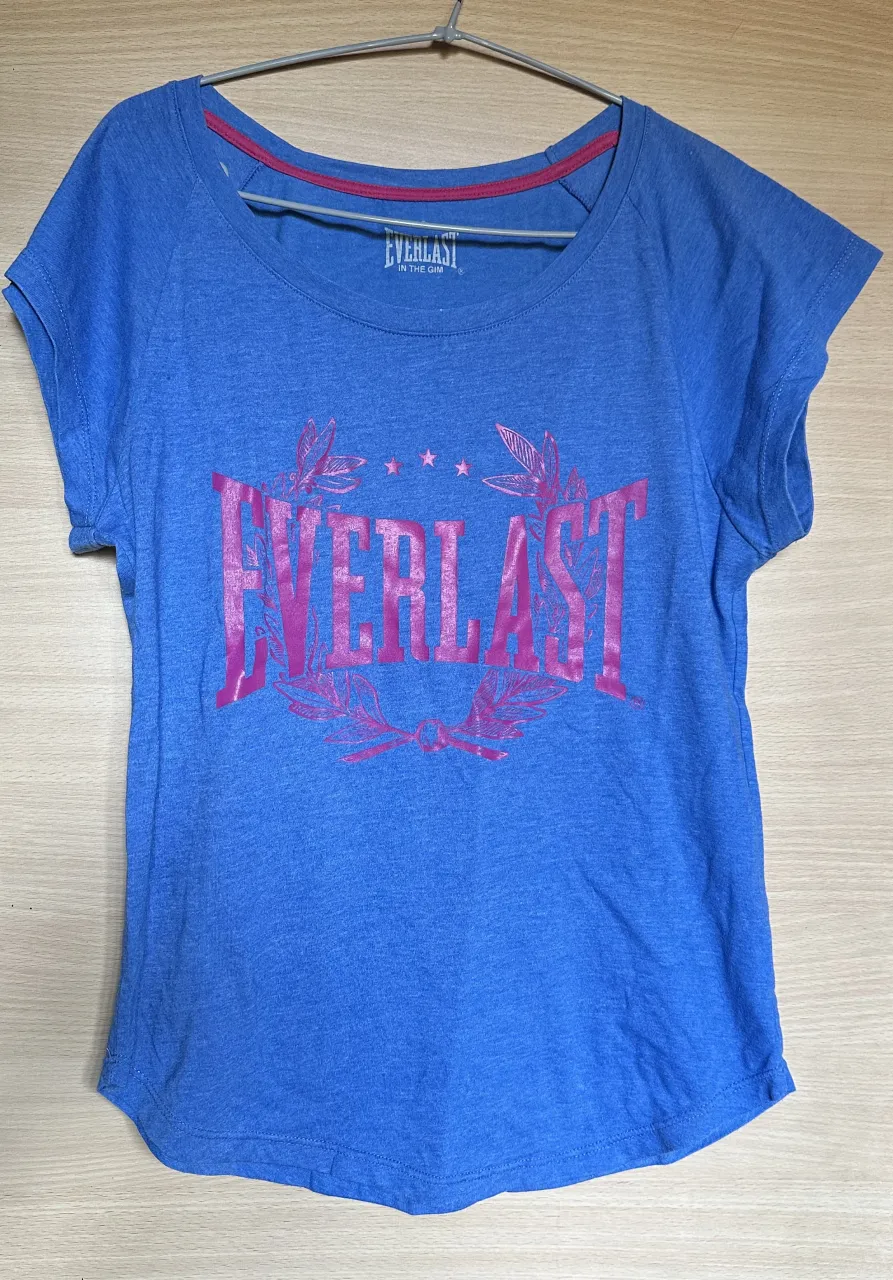 Remera azul de manga corta con estampa de "EVERLAST" en color fucsia. Cuello redondo con detalle de borde en color rosa.