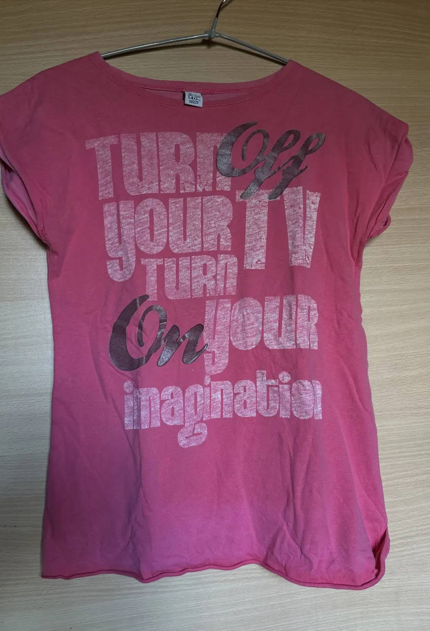 Remera rosa de algodón con estampa "Turn off your TV, turn on your imagination". Ideal para el día a día, cómoda y con un mensaje inspirador.