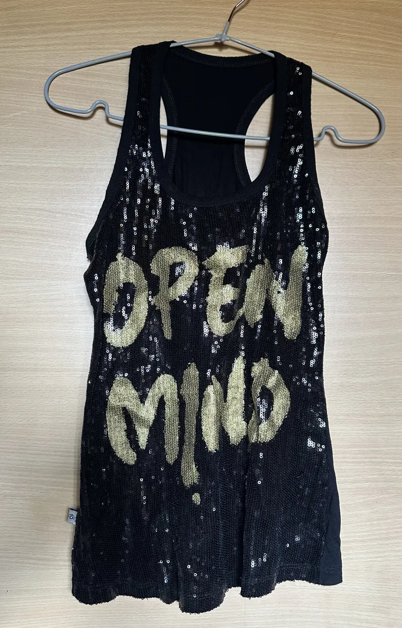 Musculosa negra con lentejuelas doradas y estampa "OPEN MIND". Ideal para un look canchero y llamativo.