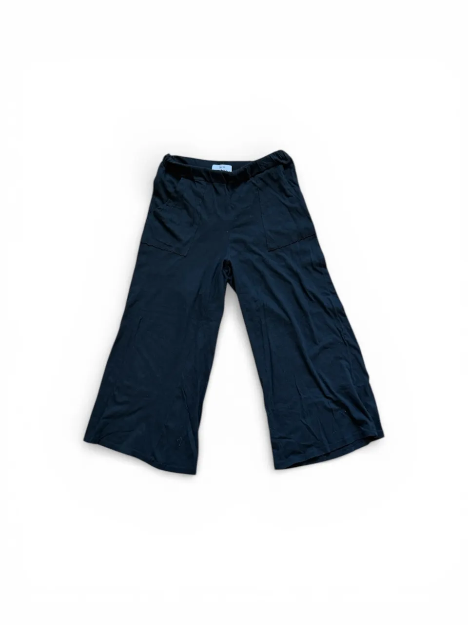 Pantalón negro de tela con bolsillos delanteros y cintura elastizada.