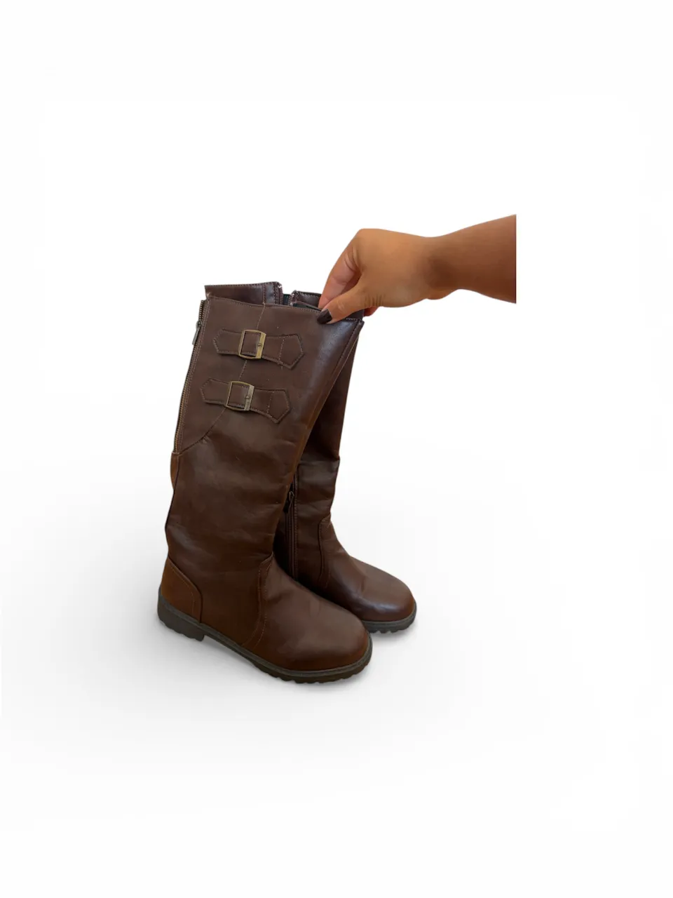 Botas marrones de caña alta con dos hebillas decorativas en el lateral y cierre en la parte trasera.