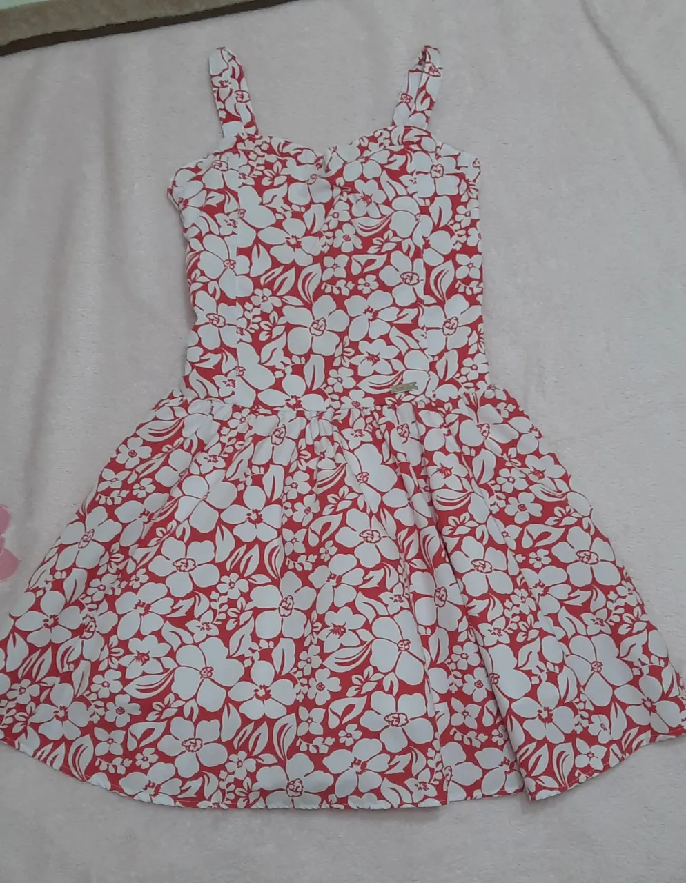 Vestido corto estampado floral en rojo y blanco, con breteles finos y falda con movimiento. La parte superior es fruncida.