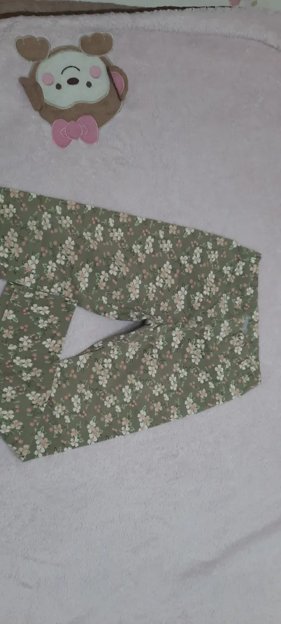 Pantalón de calce ajustado con estampa floral de flores blancas y rosas sobre fondo verde. Cintura elástica.