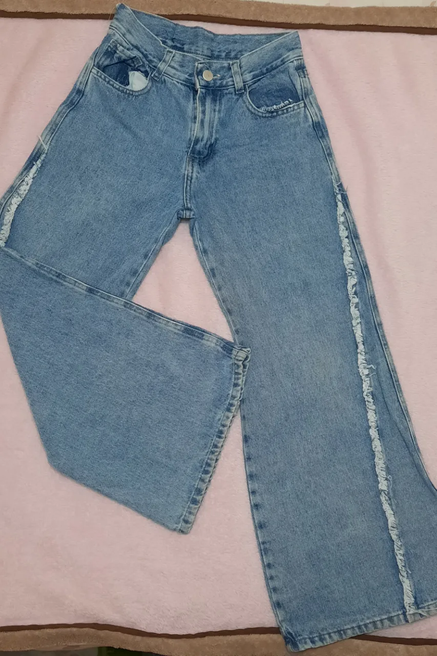 Jeans de tiro alto, con detalles de flecos en los laterales de las piernas. Lavado celeste.