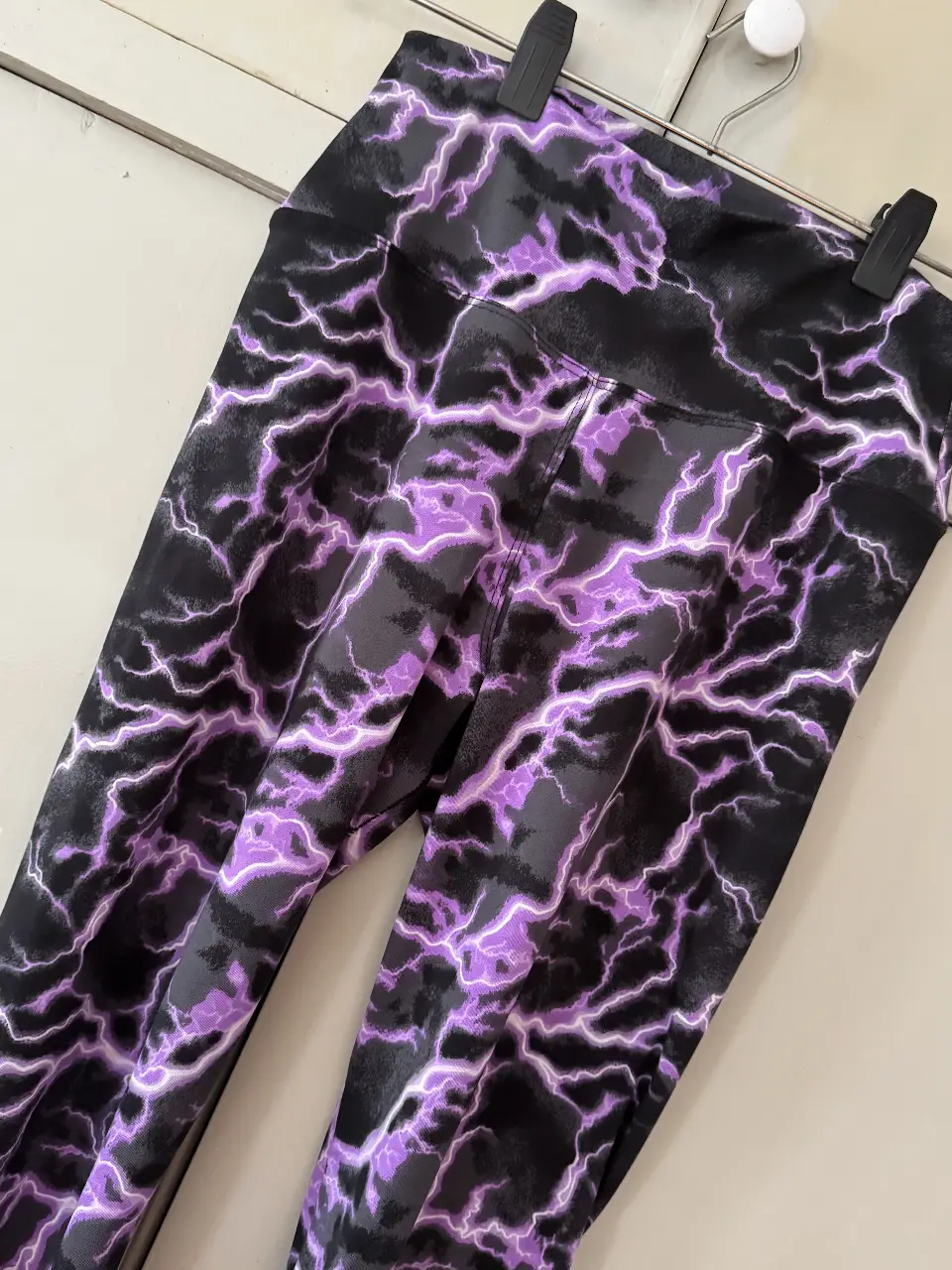 Calzas deportivas con estampado de rayos en tonos negro y violeta. Ideales para entrenamientos y actividades de alto impacto. Diseño moderno y ajuste perfecto.