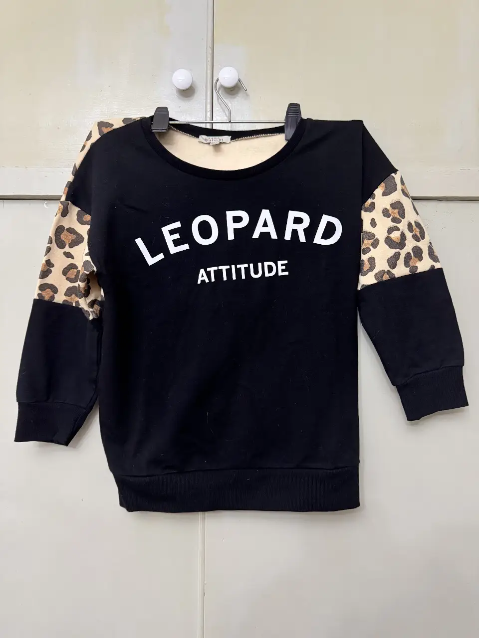 Buzo de cuello redondo negro con mangas y detalles en estampado de leopardo. La prenda es de la marca Zara Trafaluc, ideal para un look casual y moderno.