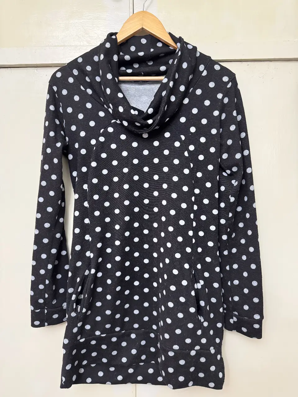 Buzo largo de mujer con estampado de lunares blancos sobre fondo negro. Cuello alto y bolsillos laterales. Ideal para un look casual y cómodo.