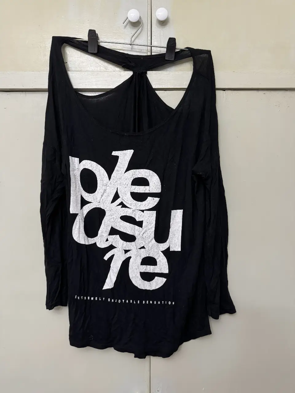 Remera manga larga negra con estampado "pleasure" en blanco. Diseño con espalda descubierta.