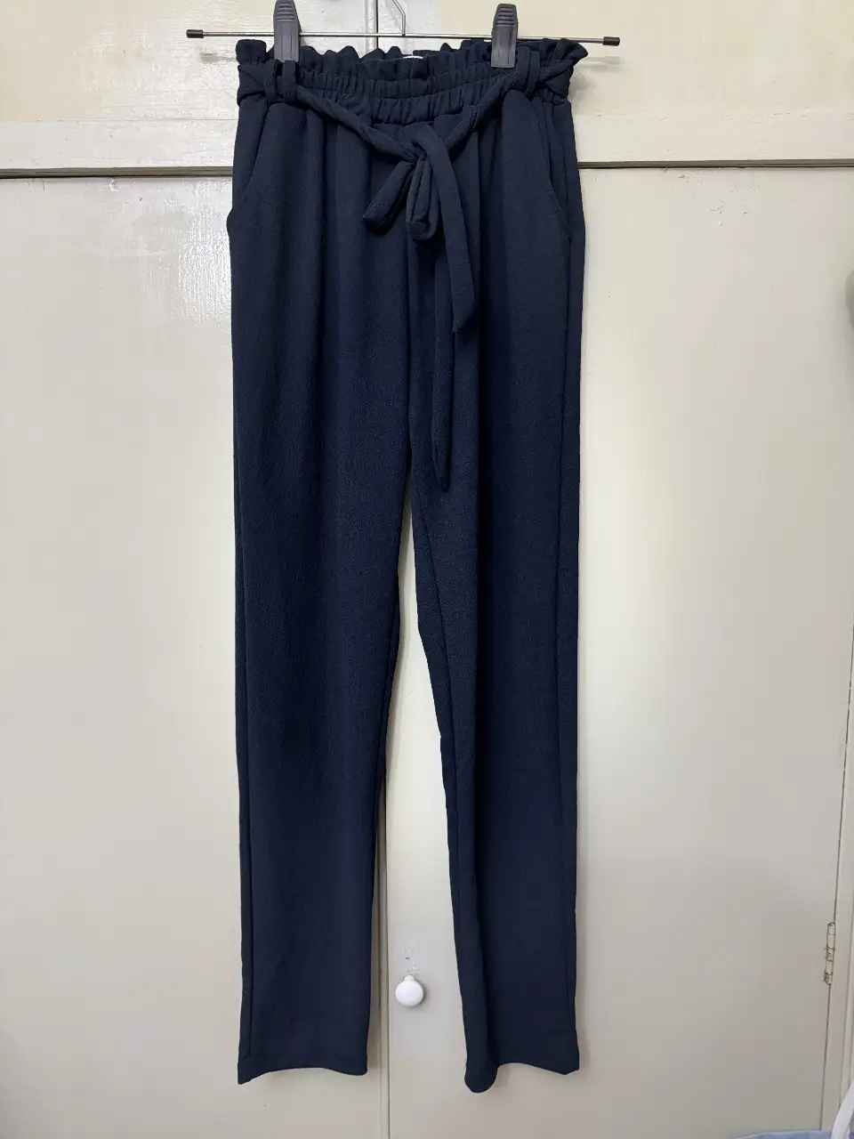 Pantalón de vestir para mujer, de color azul oscuro. Con cintura fruncida y lazo para ajustar. Bolsillos laterales. Ideal para un look elegante y cómodo.