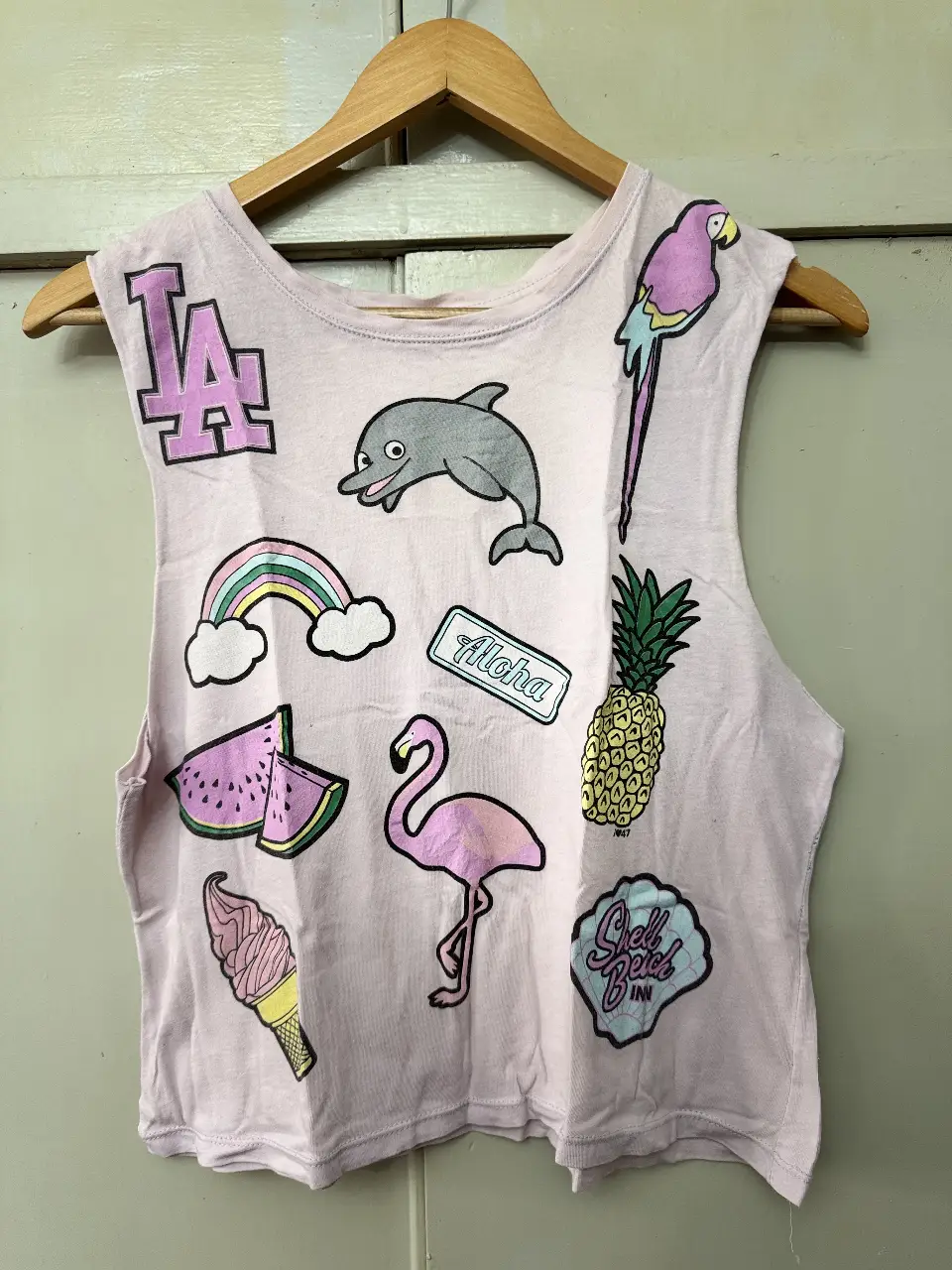 Musculosa de mujer con estampados de verano. Diseño con apliques de diferentes figuras como un delfín, un flamenco, una piña, un helado, un arcoíris y el logo de "LA". Ideal para un look casual y fresco.