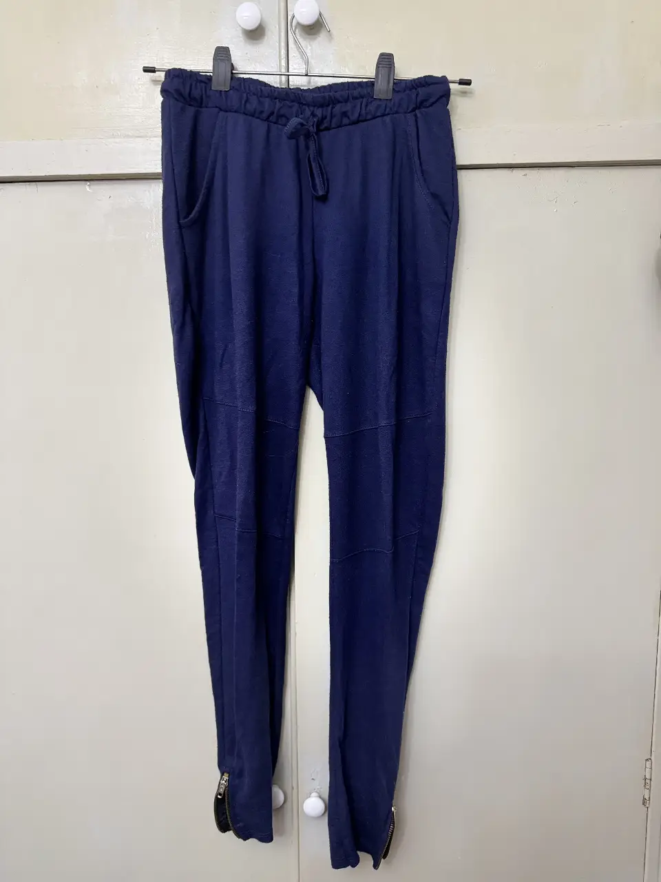 Pantalón de jogging azul marino, con cintura elastizada y cordón para ajustar. Detalles de costuras en las rodillas y cierre en los tobillos. Ideal para un look casual y cómodo.