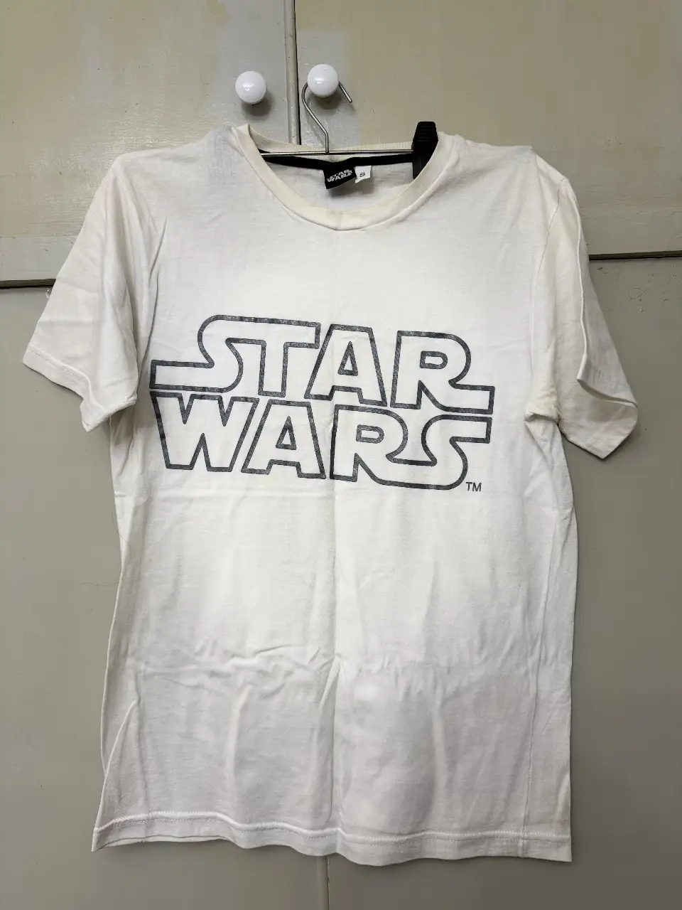 Remera blanca de manga corta con estampado del logo de Star Wars en color gris. Ideal para un look casual y cómodo. Talle S.