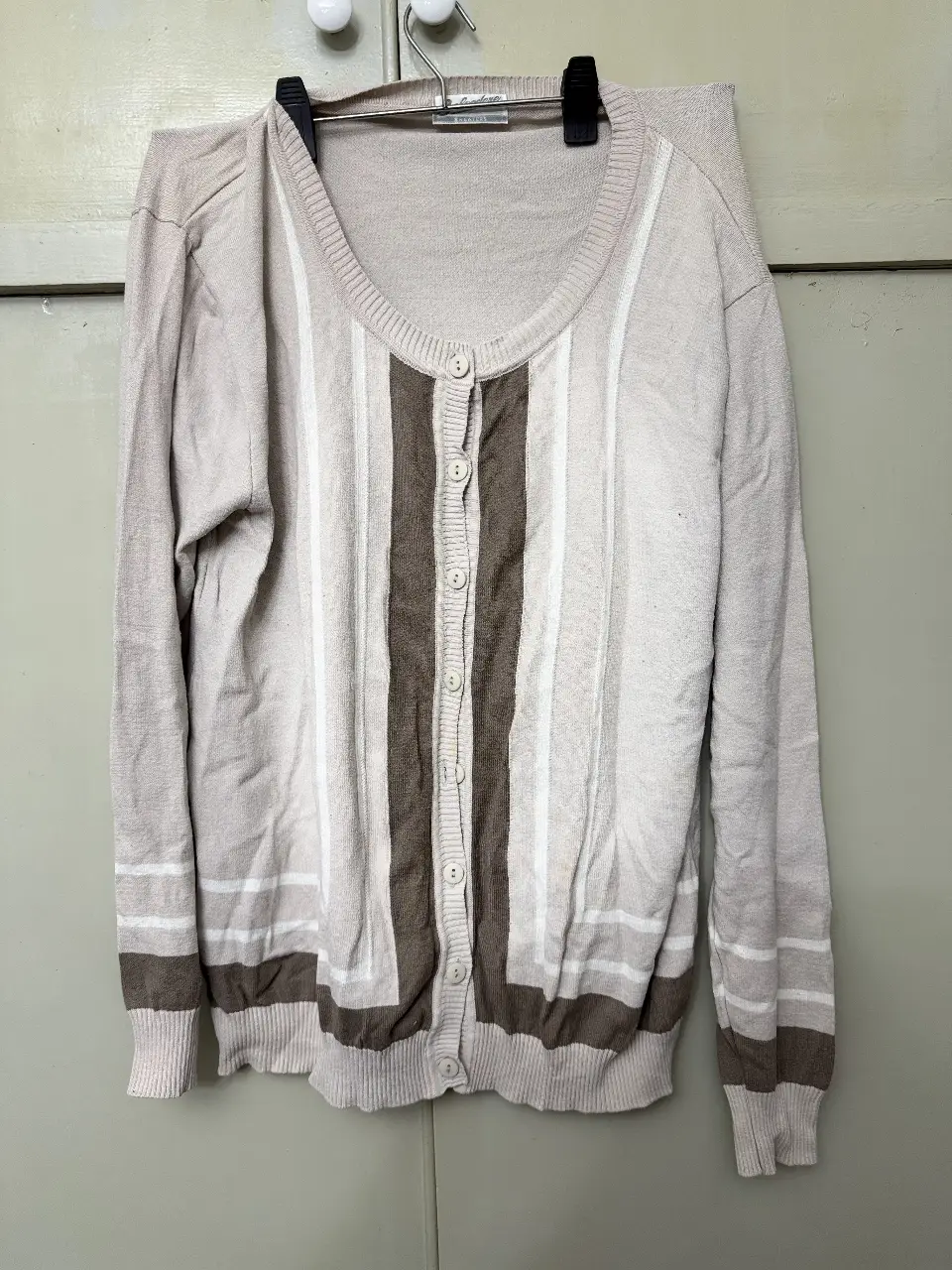 Cardigan de punto con diseño a rayas verticales en tonos crudo y marrón. Cuello redondo y cierre con botones. Ideal para un look casual y abrigado.