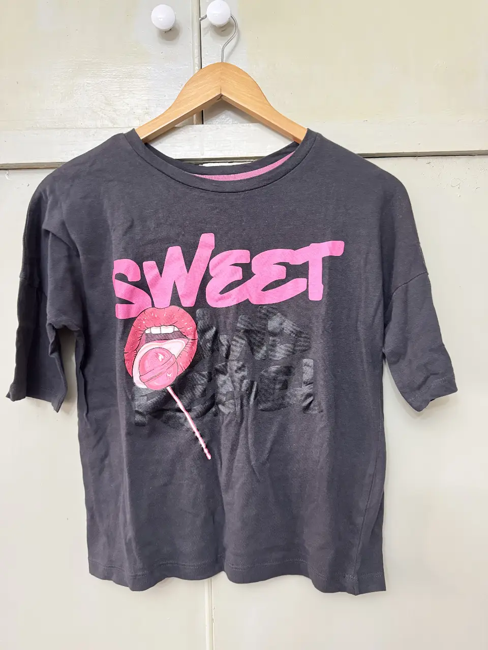 Remera de mujer gris con estampado "SWEET" en rosa y diseño de labios con chupetín. Talle XS, ideal para un look casual y moderno. Marca Inside importada de España. 