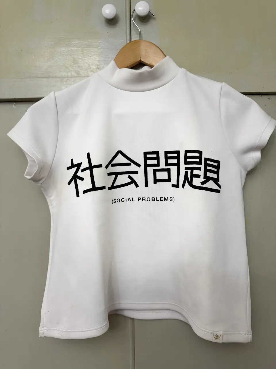 Remera blanca de cuello alto con estampado en negro. Diseño con frase en japonés '社会問題' (Social Problems). Ideal para un look minimalista y aesthetic. 