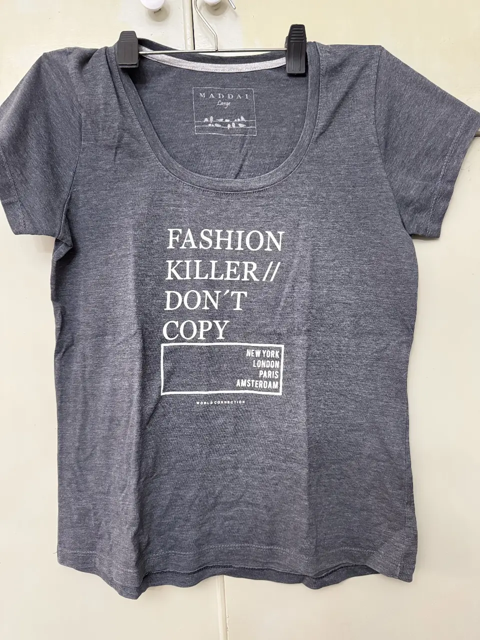 Remera de mujer de color gris con estampado "Fashion Killer // Don't Copy" y detalles de ciudades como New York, London, Paris y Amsterdam. Marca Maddai.