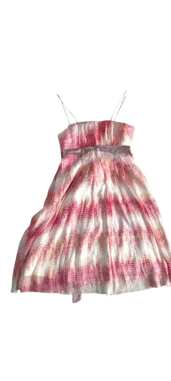 Vestido a la rodilla, breteles finos, escote recto, ideal para eventos de día o noche. Posee un estampado vibrante en tonos rosas y blancos, con un lazo de raso delicado en la cintura que realza la figura. Su diseño es fresco y femenino, perfecto para lucir en primavera o verano.