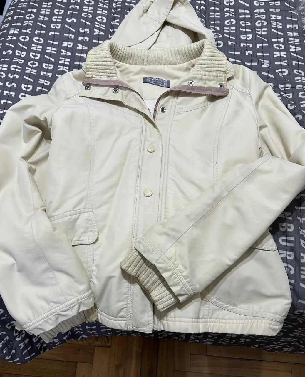 Campera beige con capucha, ideal para el invierno. Posee cierre y botones, con bolsillos delanteros. Perfecta para un look casual y abrigado.