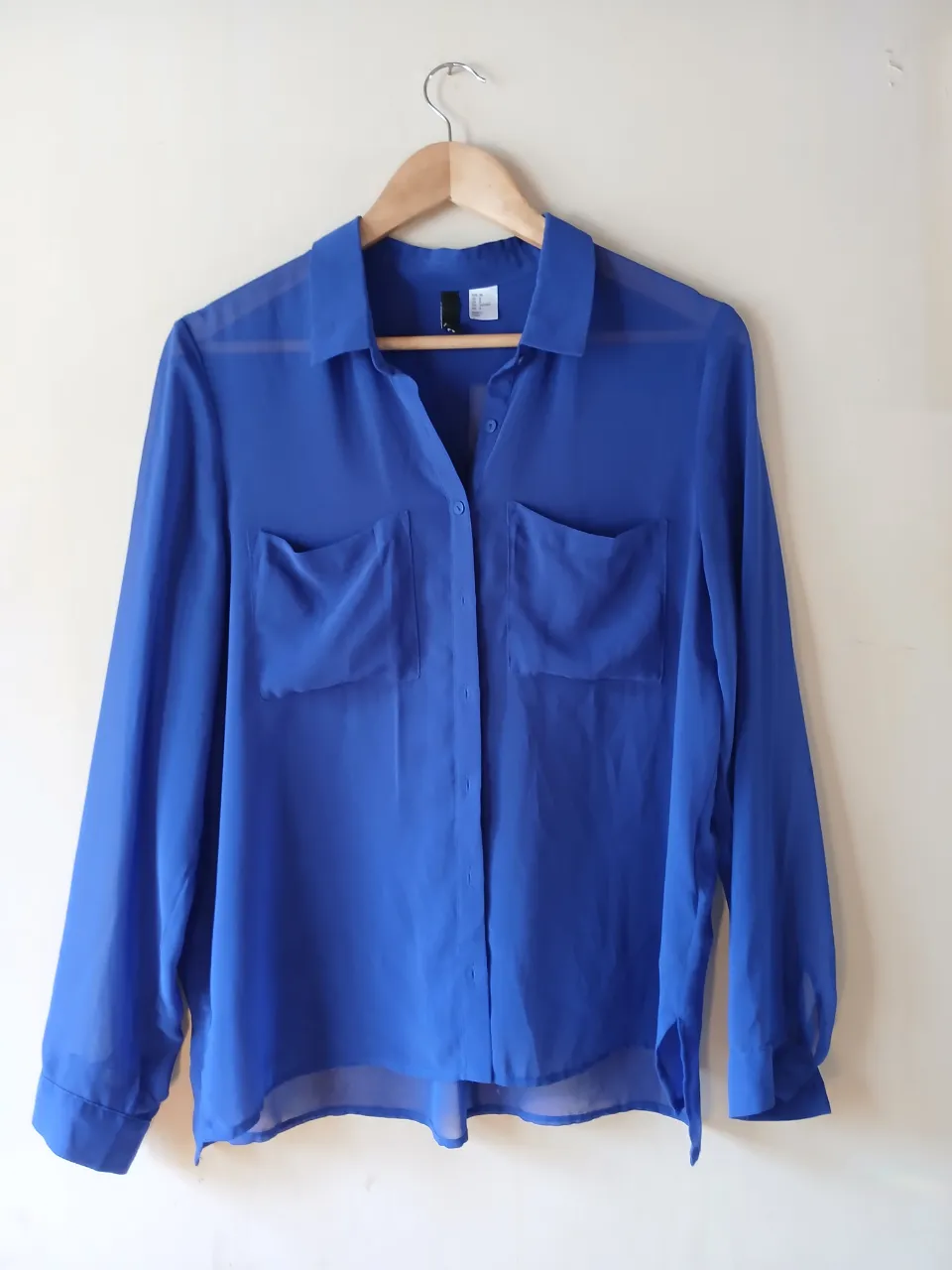 Blusa azul de gasa, con dos bolsillos delanteros y cuello camisero. Ideal para un look elegante y fresco.