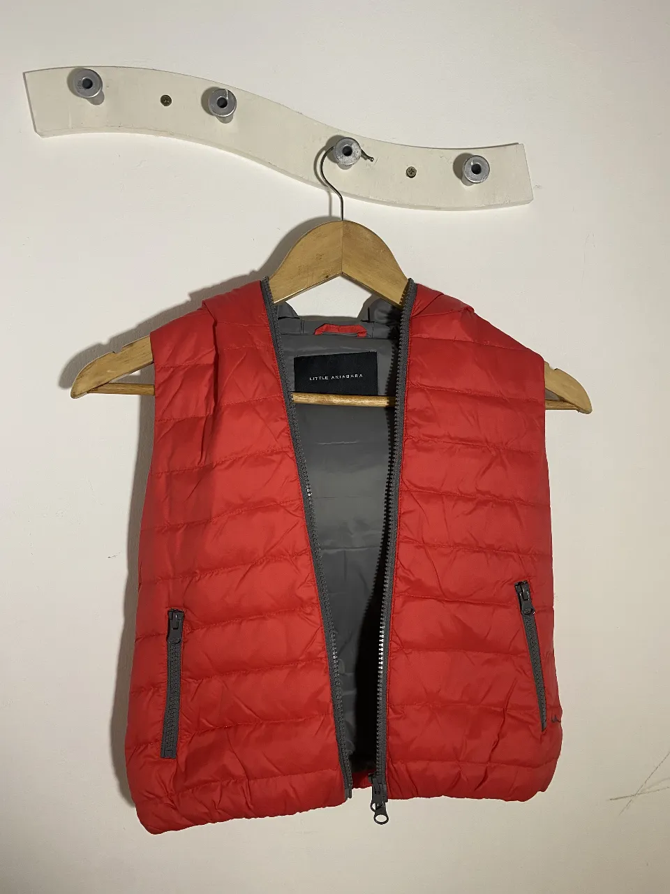 Chaleco Little Akiabara, acolchado, rojo con interior gris, con capucha y bolsillos con cierre. Ideal para abrigo ligero y cómodo.