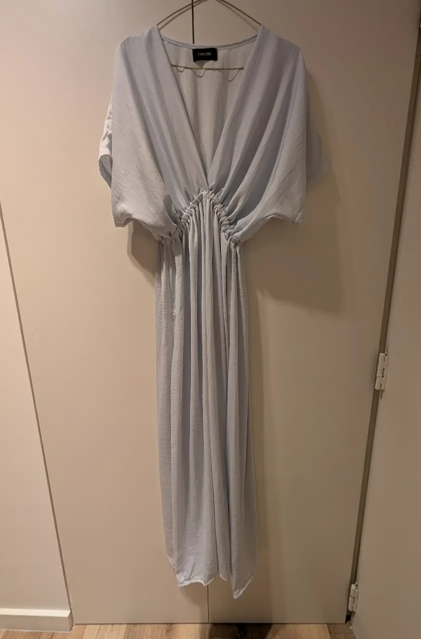 Vestido largo de color celeste claro, con escote en V y detalle fruncido en la cintura. Mangas amplias tipo murciélago. Ideal para eventos especiales o salidas elegantes.
