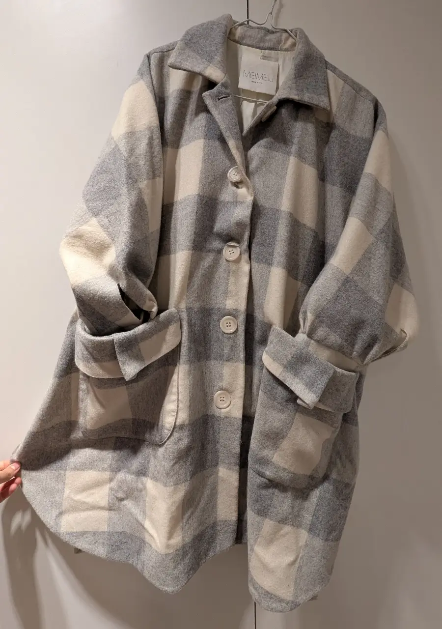 Tapado de paño italiano  con diseño a cuadros en tonos grises y blancos. Posee bolsillos delanteros y botones. Ideal para un look casual y abrigado.