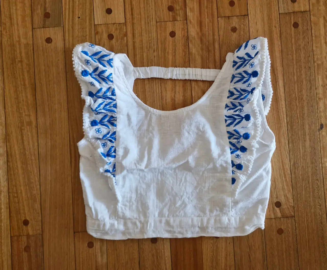 Top blanco con bordado azul, ideal para un look fresco y casual. Perfecto para el verano.