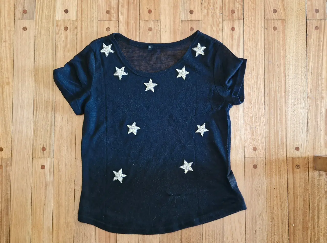 Remera negra con estrellas plateadas. La tela es medio transparente. La tela es una lanilla muy fina