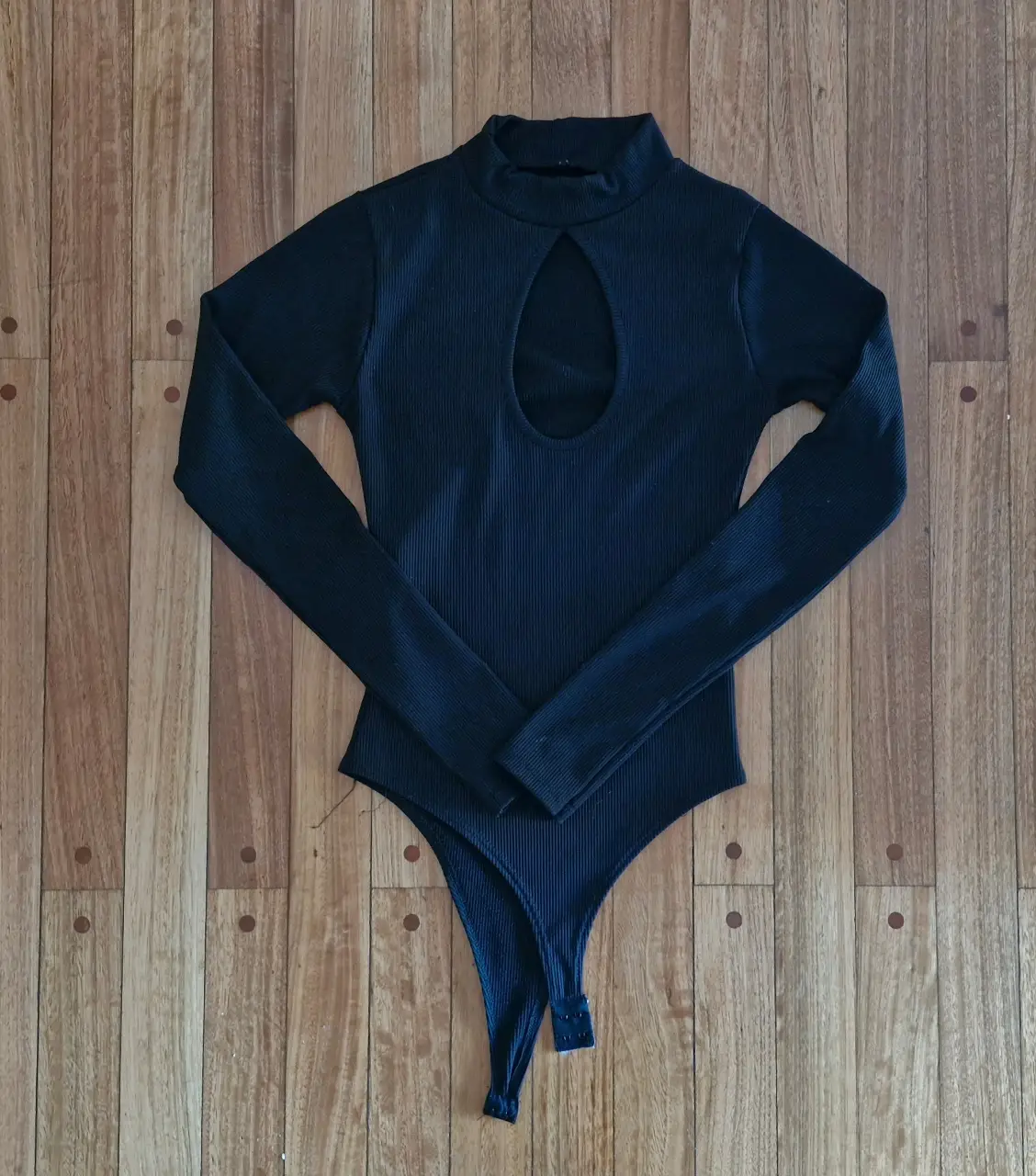 Body negro de manga larga con cuello alto y abertura en el pecho. Ideal para un look moderno y sofisticado.