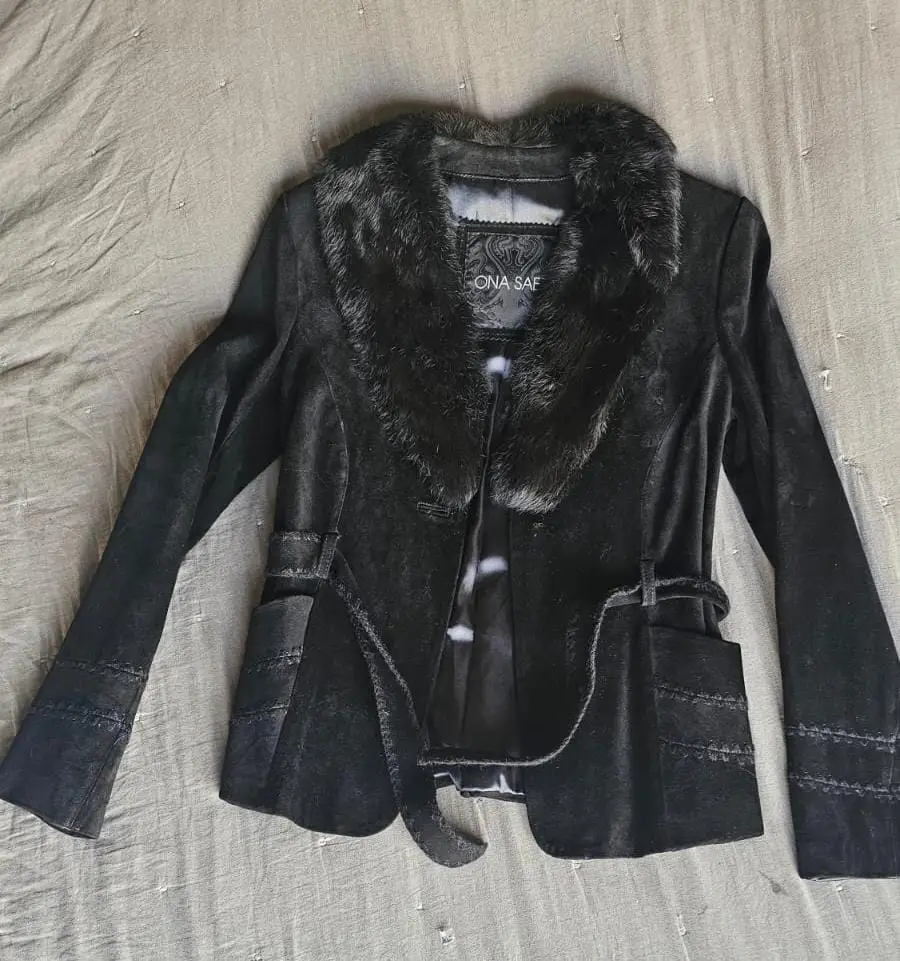 Campera de mujer negra de terciopelo con cuello de piel sintética. Detalles de costuras y cinturón. Ideal para un look elegante y sofisticado.
