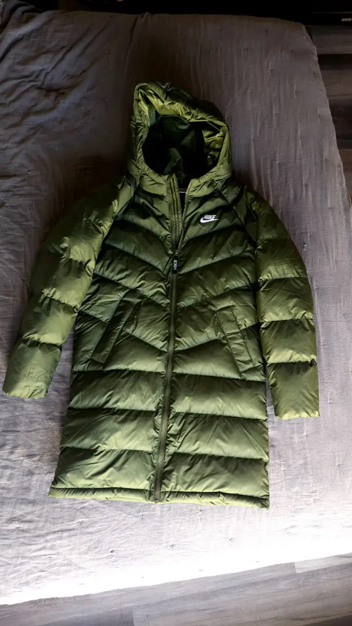 Campera Nike larga de pluma, color verde militar, con capucha y cierre. Ideal para el invierno.