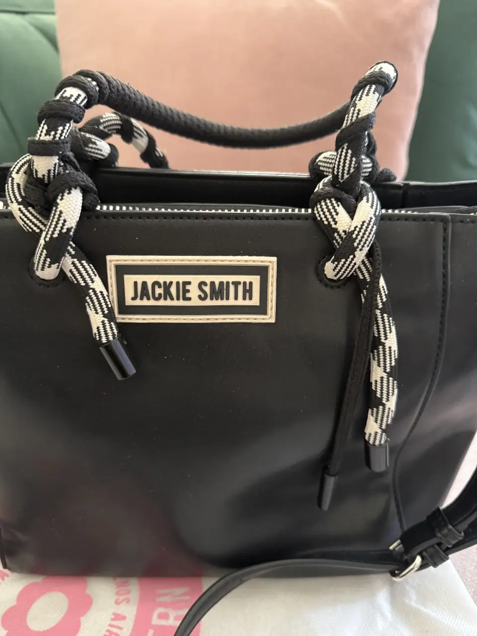 Cartera Jackie Smith negra con manijas trenzadas en blanco y negro. Ideal para llevar al hombro o cruzada. Diseño moderno y funcional. incluye su bolsa guardapolvo