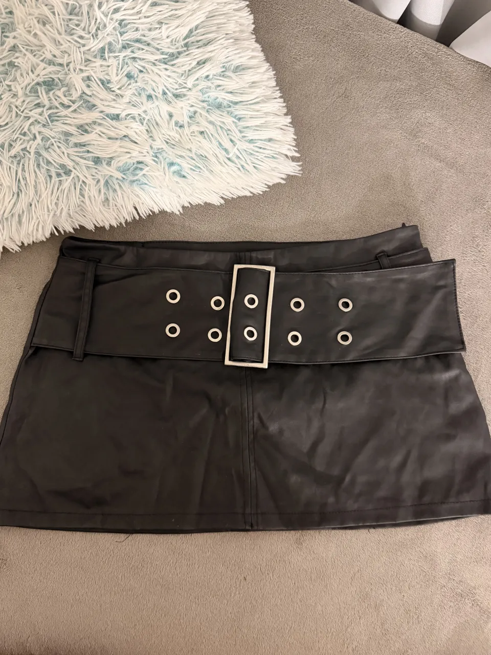 Pollera corta de cuero sintético negra, con detalles de tachas y hebilla metálica en la cintura. Un diseño audaz y moderno, ideal para looks cancheros y con actitud.