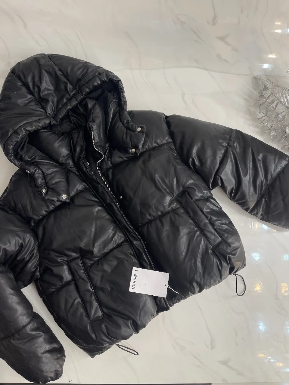 Campera puffer negra con capucha, ideal para el invierno. Marca Bershka, con cierre y detalles.