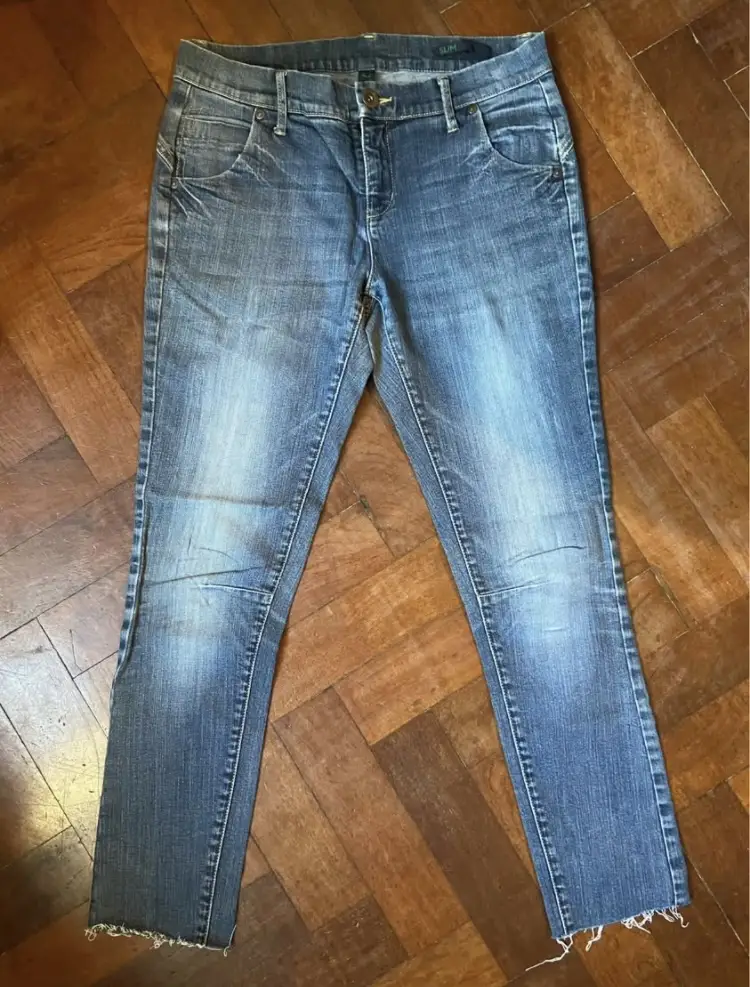Jeans rectos de mujer, color azul, con detalles de desgaste y corte desflecado en el bajo. Talle 27.