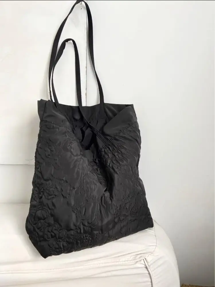 Bolso tote negro con textura en relieve, ideal para llevar todo lo que necesitas con estilo. Perfecto para un look casual y moderno.