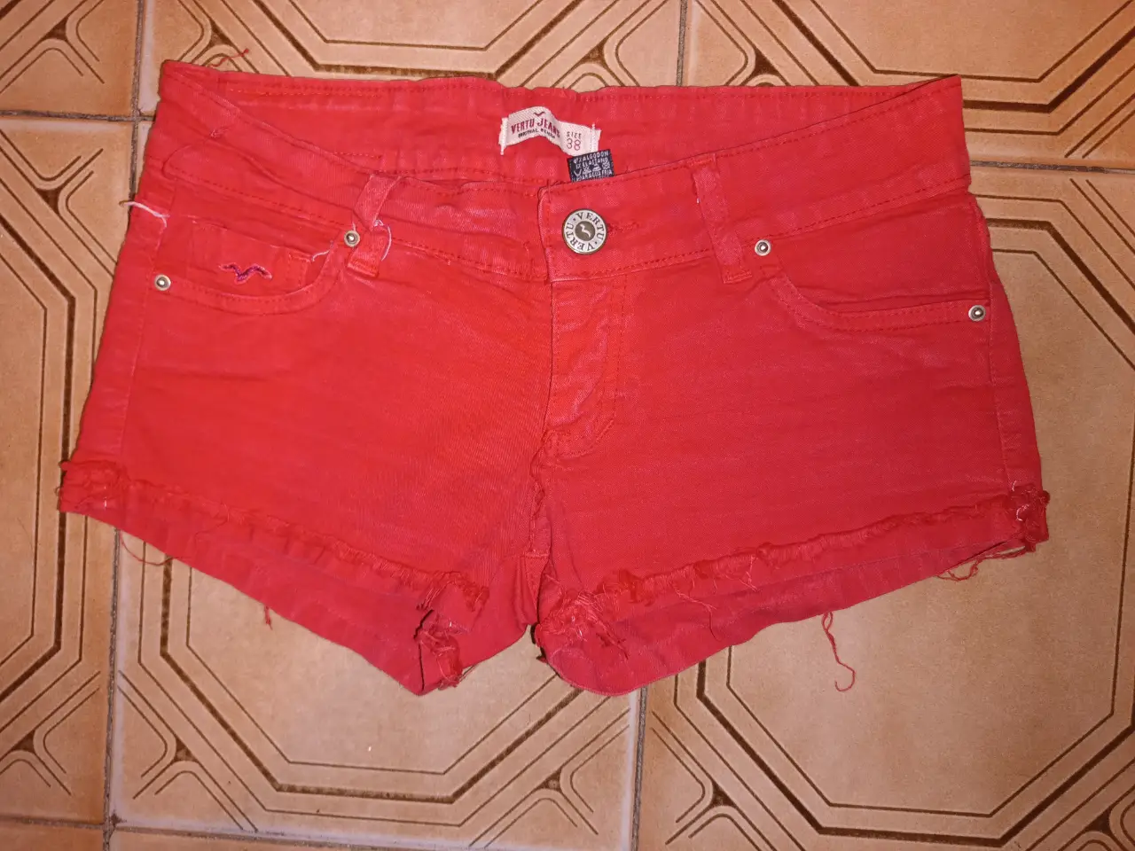 Short bien corto de jean elastizado rojo de la marca Vertu Jeans talle 38. Ideal para un look casual y moderno. Con detalles de desflecado en los bordes. Bolsillos traseros bordados. Tiro bajo, con cierre y botón. Cintura baja:74cm Cadera:88cm (cede) Tiro delantero:18cm Tiro trasero: 29cm Largo:21cm