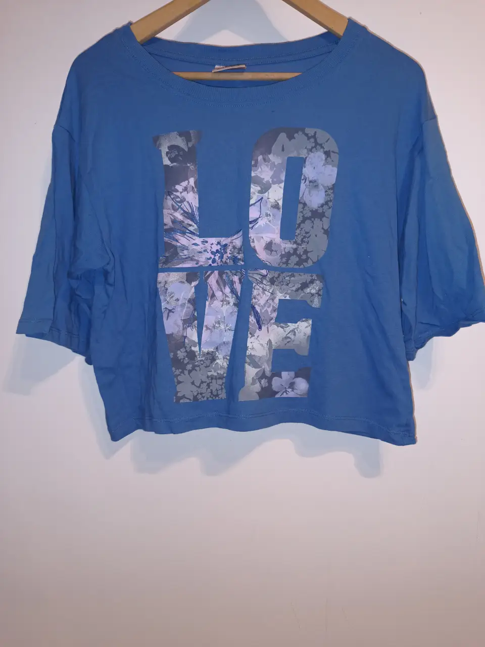 Remera azul de algodón con estampado "LOVE" en tonos florales. Corte crop, ideal para un look casual y moderno. Talle L. Muy buen estado. Entre sisas:56 Largo:53cm