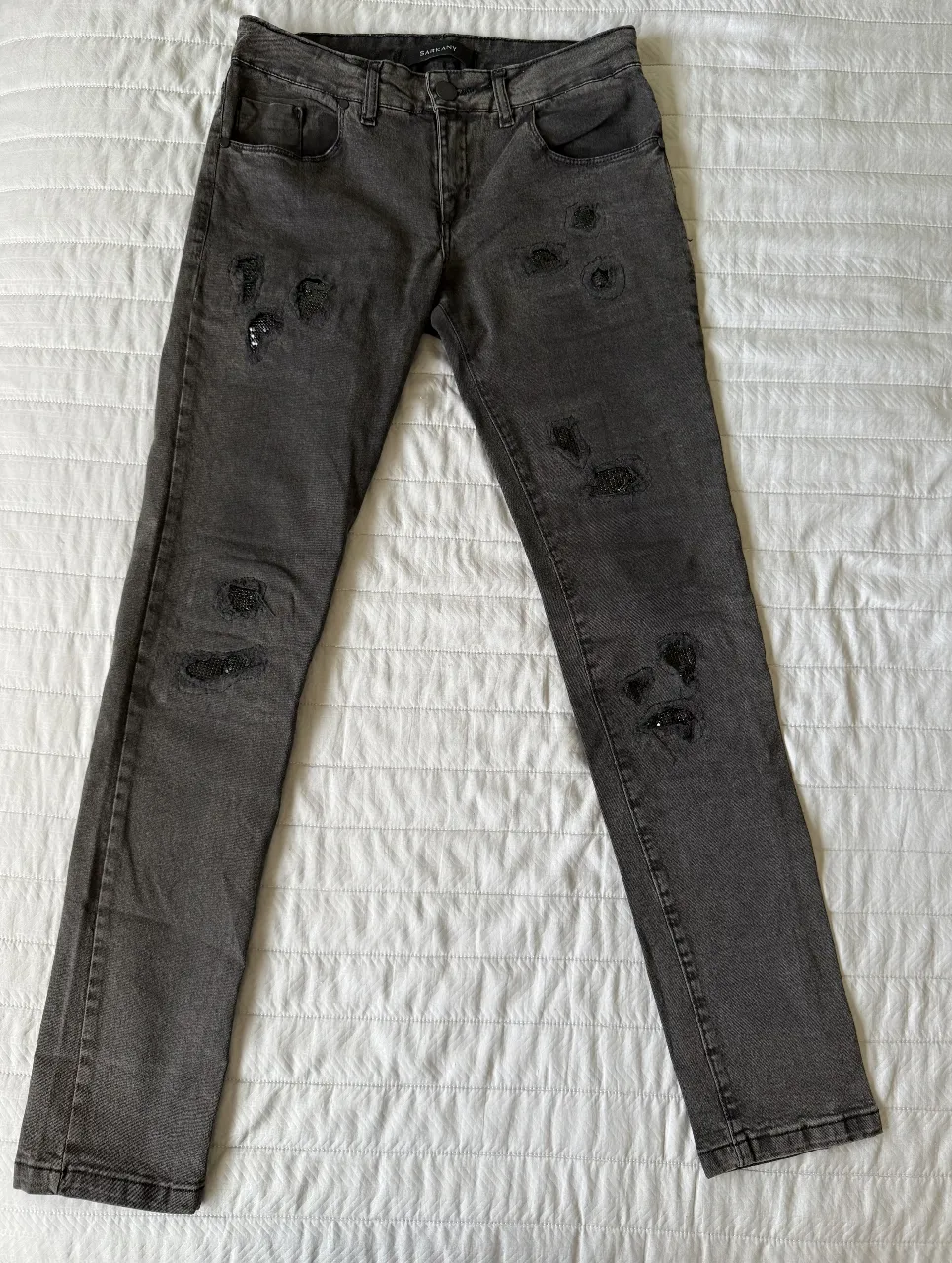 Skinny jean negro de mujer de Sarkany con roturas y detalles de brillo metalizado. Talle 29. 