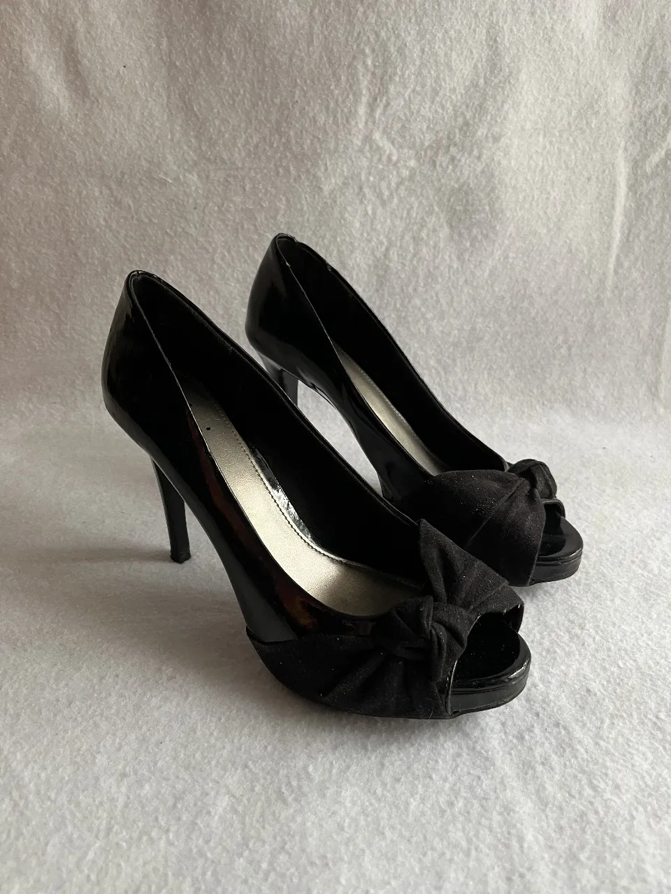 Elegantes zapatos de taco alto negros con detalle de moño en la punta. Ideales para eventos formales y fiestas.