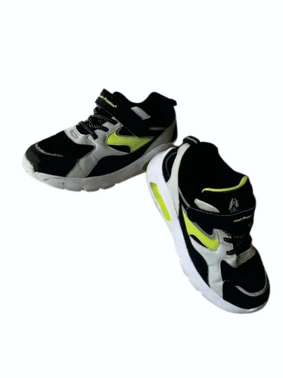 Zapatillas Hush Puppies para niños, negras con detalles en gris y amarillo. Ideales para uso diario y actividades deportivas.