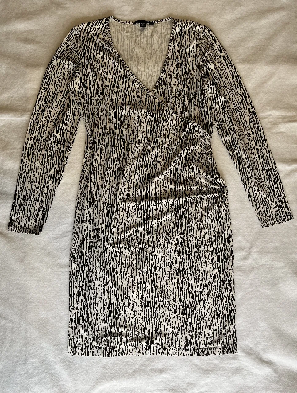 Vestido midi con estampado abstracto en blanco y negro. Diseño con escote en V y mangas largas. Ideal para un look elegante y versátil.