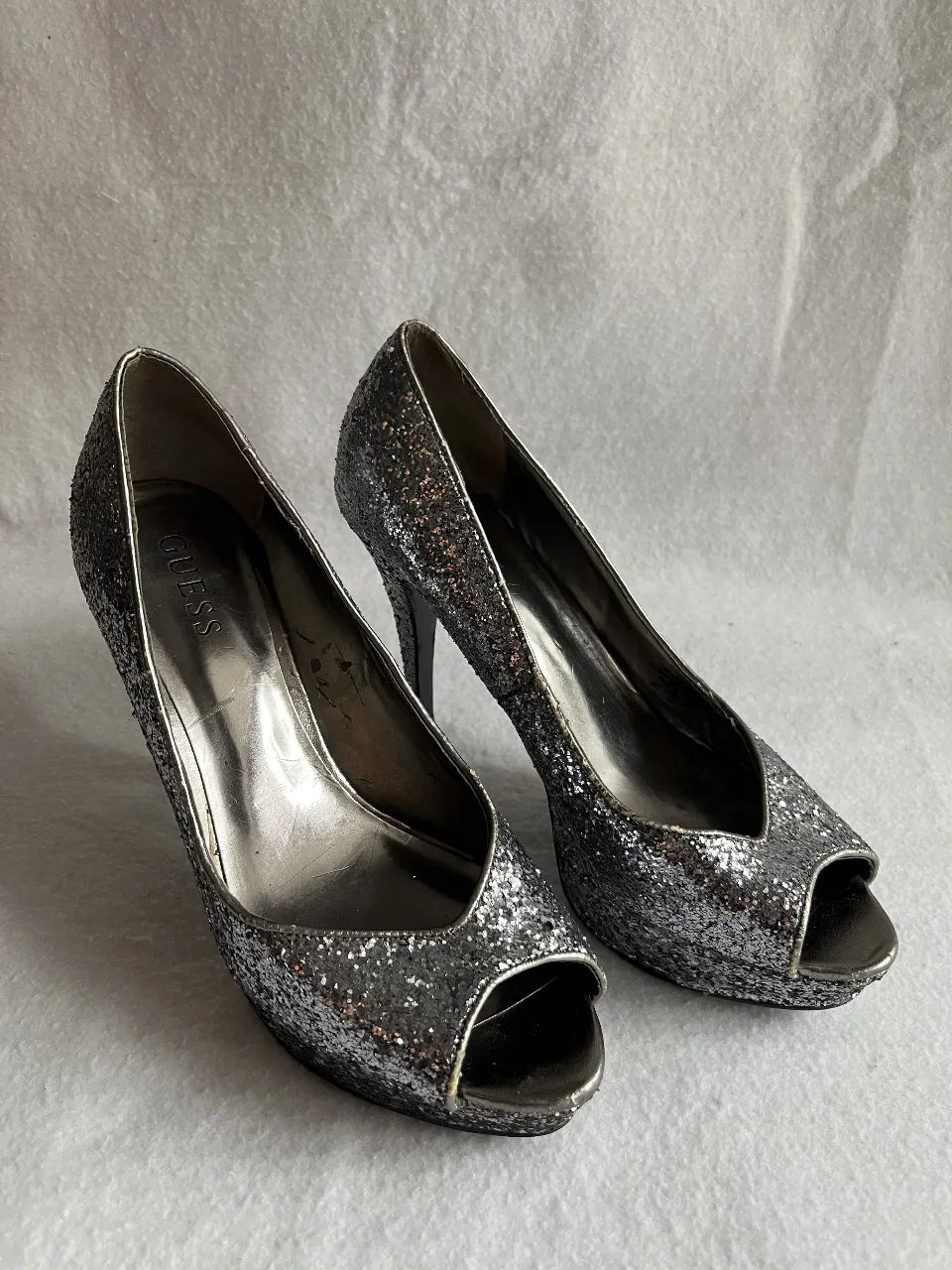 Zapatos de tacón Guess con brillo plateado, ideales para fiestas y eventos especiales. Diseño elegante y moderno.