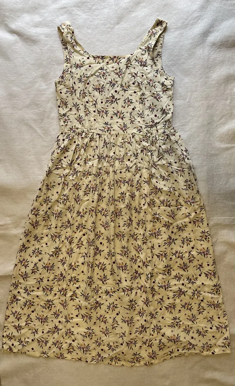 Vestido midi de tela liviana con estampado floral en tonos rojos y beige. Corte a la cintura y falda con vuelo, ideal para un look fresco y femenino.
