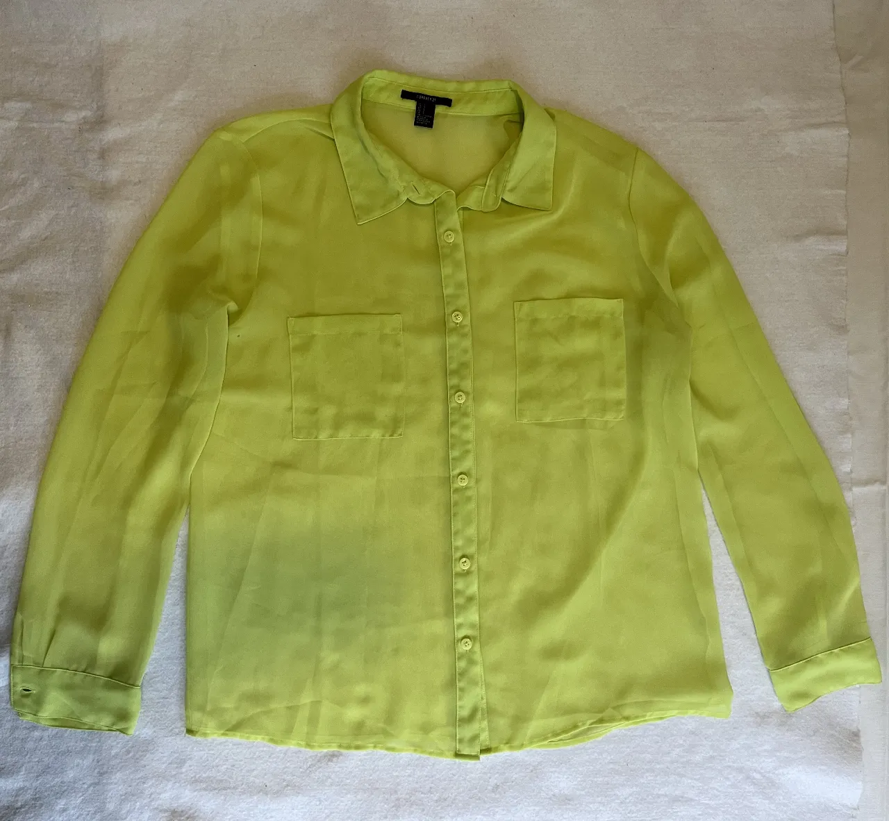 Blusa de mujer, color verde lima, con mangas largas y dos bolsillos delanteros. Ideal para un look casual y fresco.