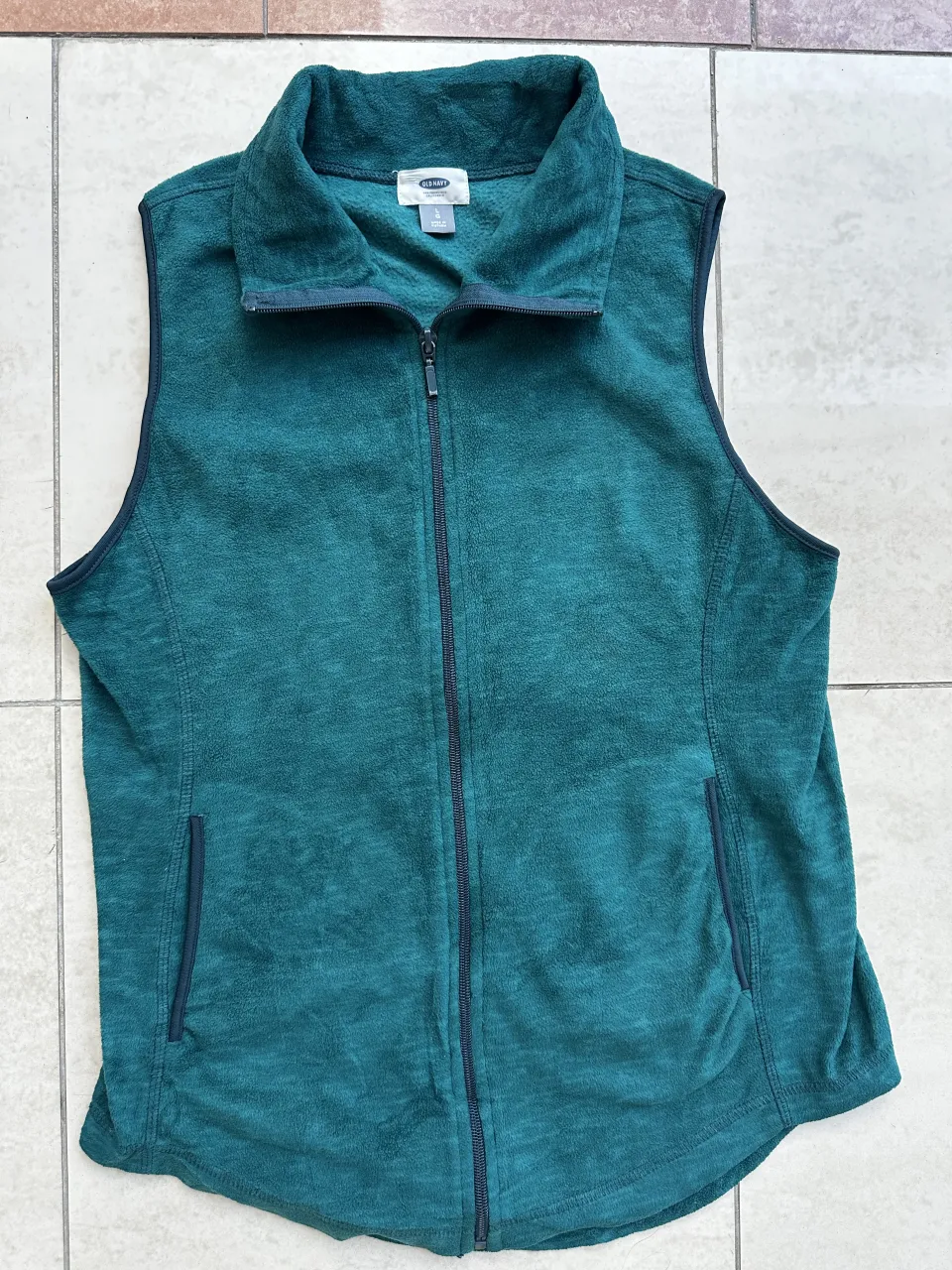 Chaleco de polar verde con cierre completo y cuello alto. Posee dos bolsillos laterales con cierre.