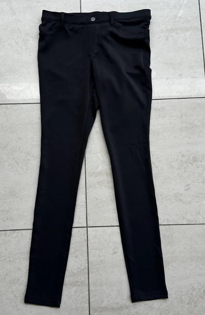 Pantalón negro liso con bolsillos delanteros y traseros.