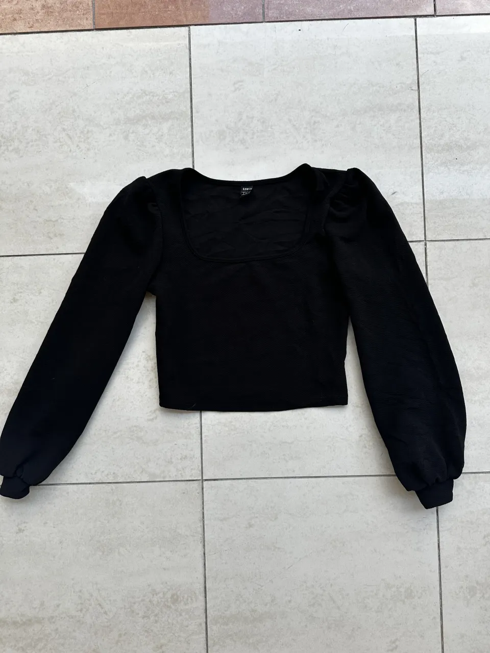 Remera negra manga larga con escote cuadrado y mangas abullonadas.